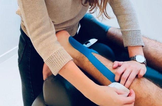 Uw kinesist in Sint-Niklaas - Kinesitherapie Re-flex Foto van kinesiste Stephanie De Greef die in haar praktijk in Sint-Niklaas de achterkant van een been tapet