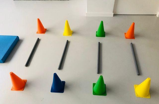 Kinesitherapie Re-flex - Afbeelding van een oefening met kegels en overstap stokjes Afbeelding van een oefening met kegels en overstap stokjes